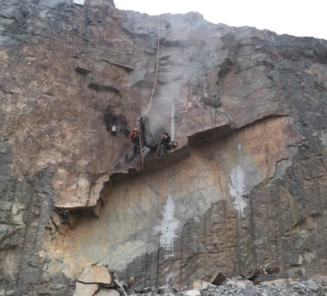 Workers drilling pit wall using rope access