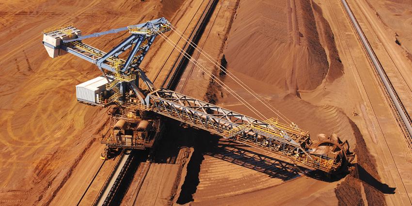 The image shows large mining equipment, specifically a bucket-wheel excavator, in an open-pit mine.
